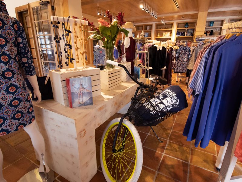 Women's clothing and necklaces on display next to a bike