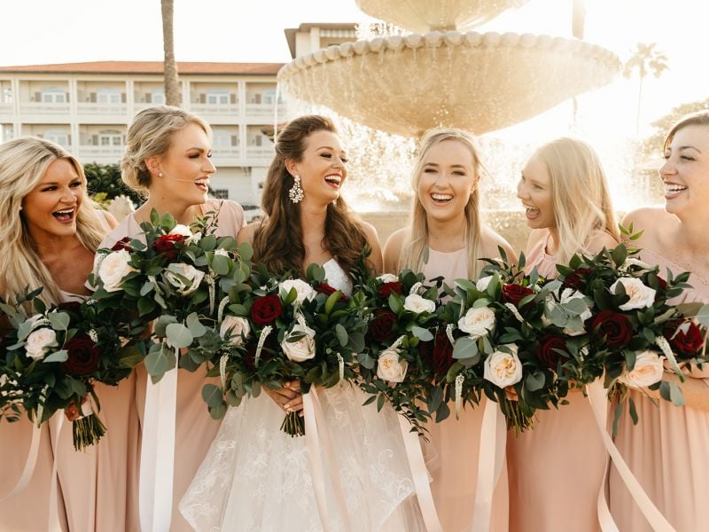 bride and bridesmaids pose in front of fountain