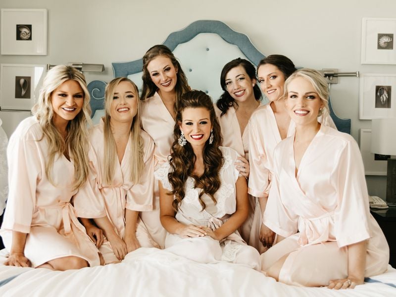 bride and bridesmaids in robes on bed