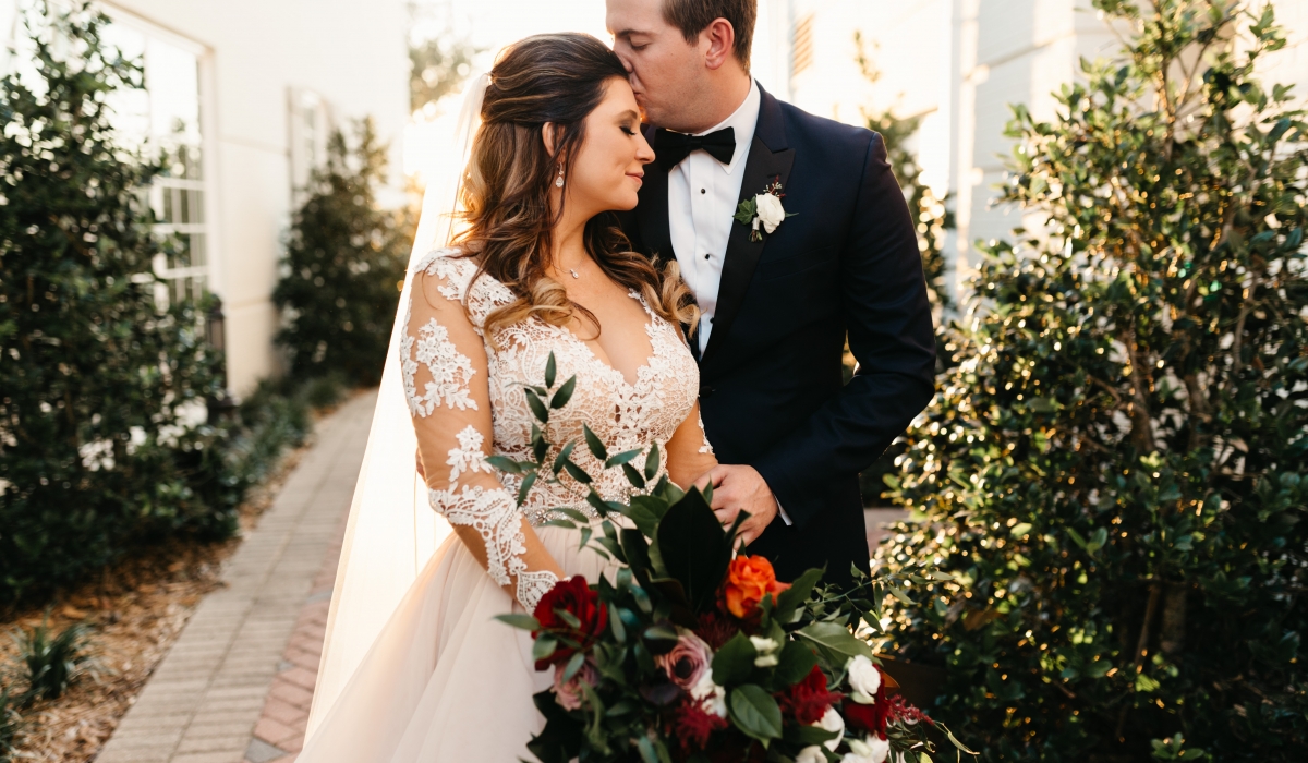 A bride smiles as her groom kisses her forehead at Ponte Vedra Inn & Club.