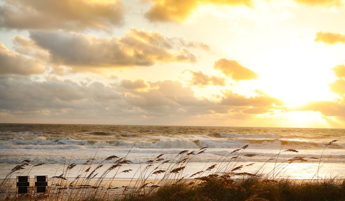 View of the beach at the Inn through dune grass near sunset