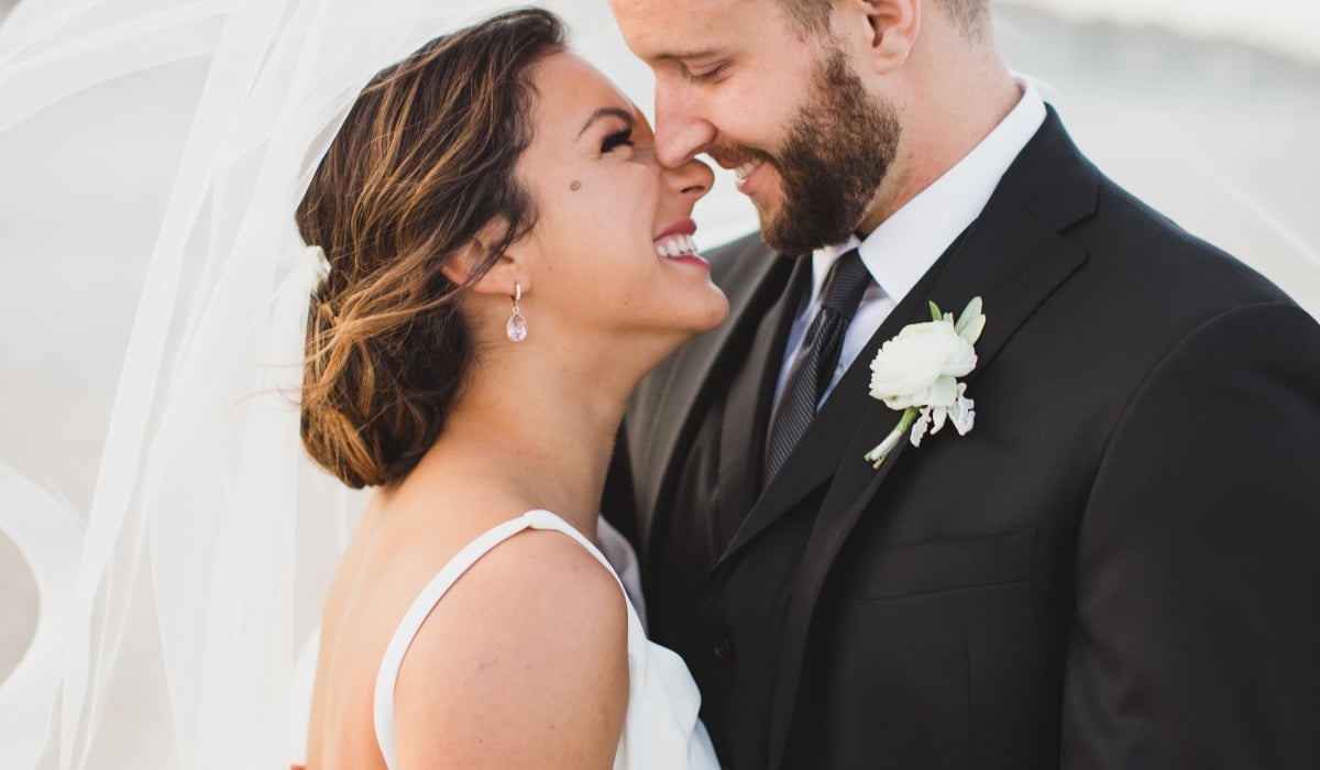 Under the bride's swirling veil, a couple embrace on the beach at Ponte Vedra Inn & Club.