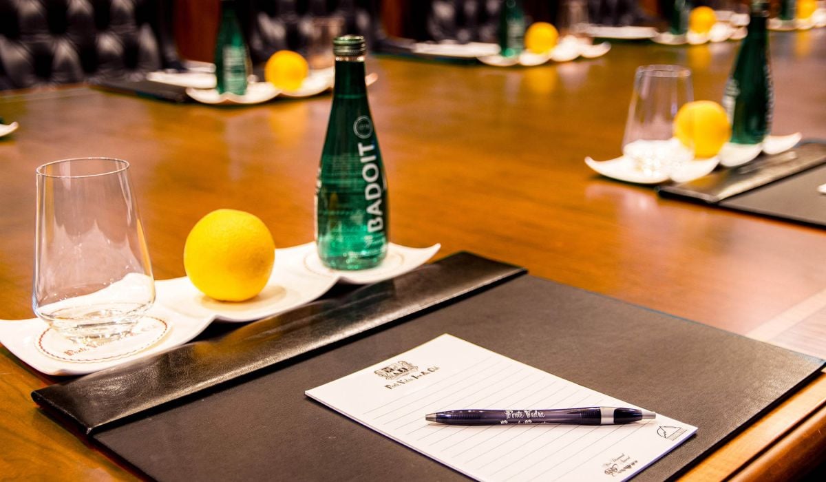 Close up of a notepad and pen, glass, lemon and carbonated water on a meeting table