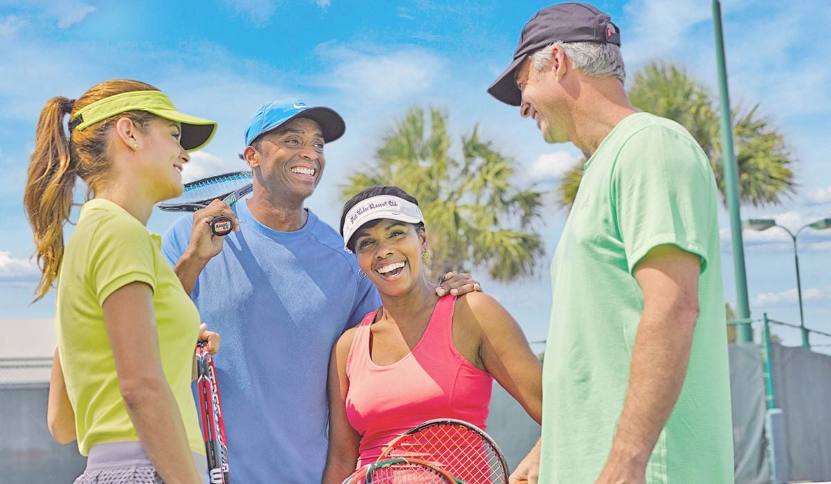 Couples laugh while playing tennis