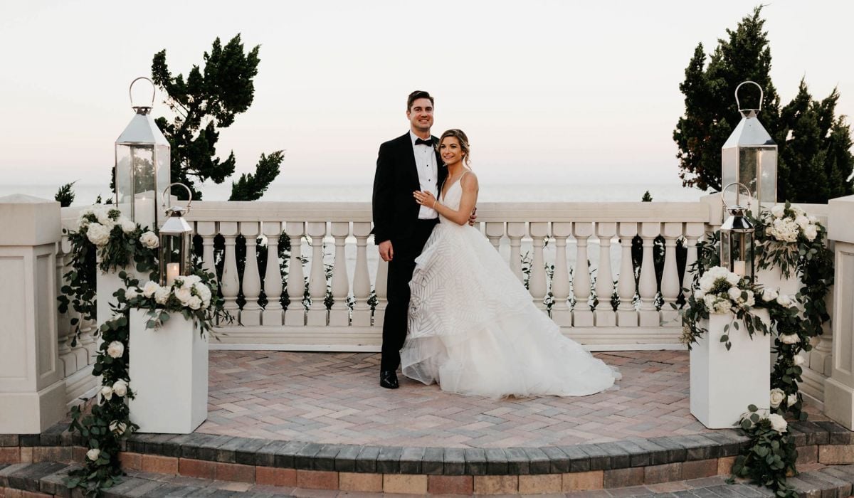A bride and groom stand surrounded by flowers and the oceanfront courtyard at Ponte Vedra Inn & Club.
