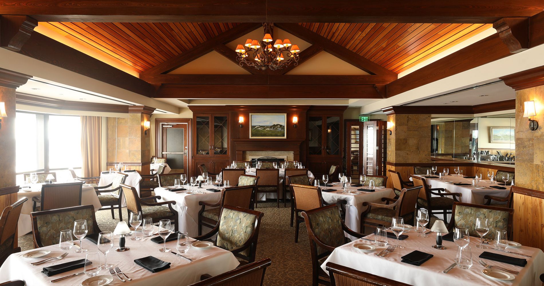 Set tables in a restaurant with a high, wood paneled ceiling
